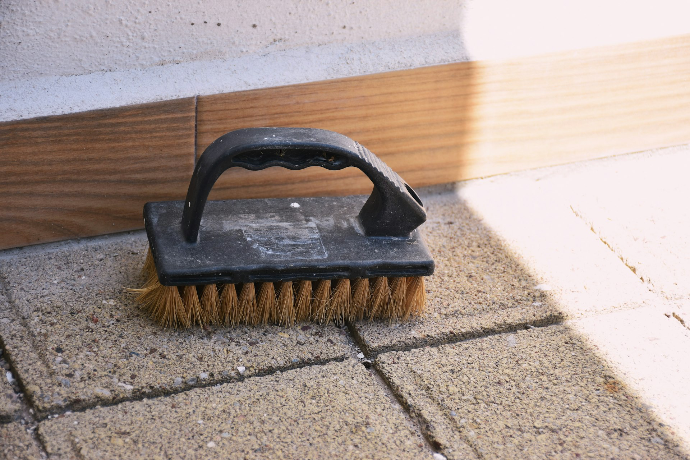 A black handled scrubbing brush on paving stones
